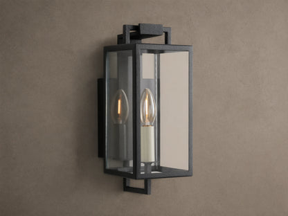 Hendricks Outdoor Sconce: black iron rectangular lantern, clear glass, two candle-style bulbs, mounted on a taupe wall.