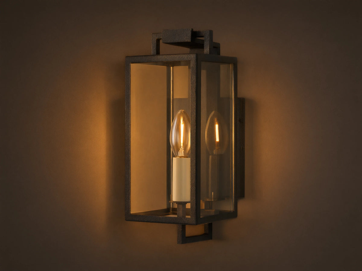 Hendricks Outdoor Sconce: black iron rectangular lantern, clear glass, two candle-style bulbs, mounted on a taupe wall.
