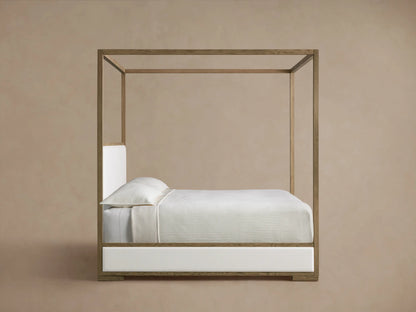 Detailed view of Darien Canopy Bed's light oak wood frame with visible grain, bordering a textured off-white upholstered panel.