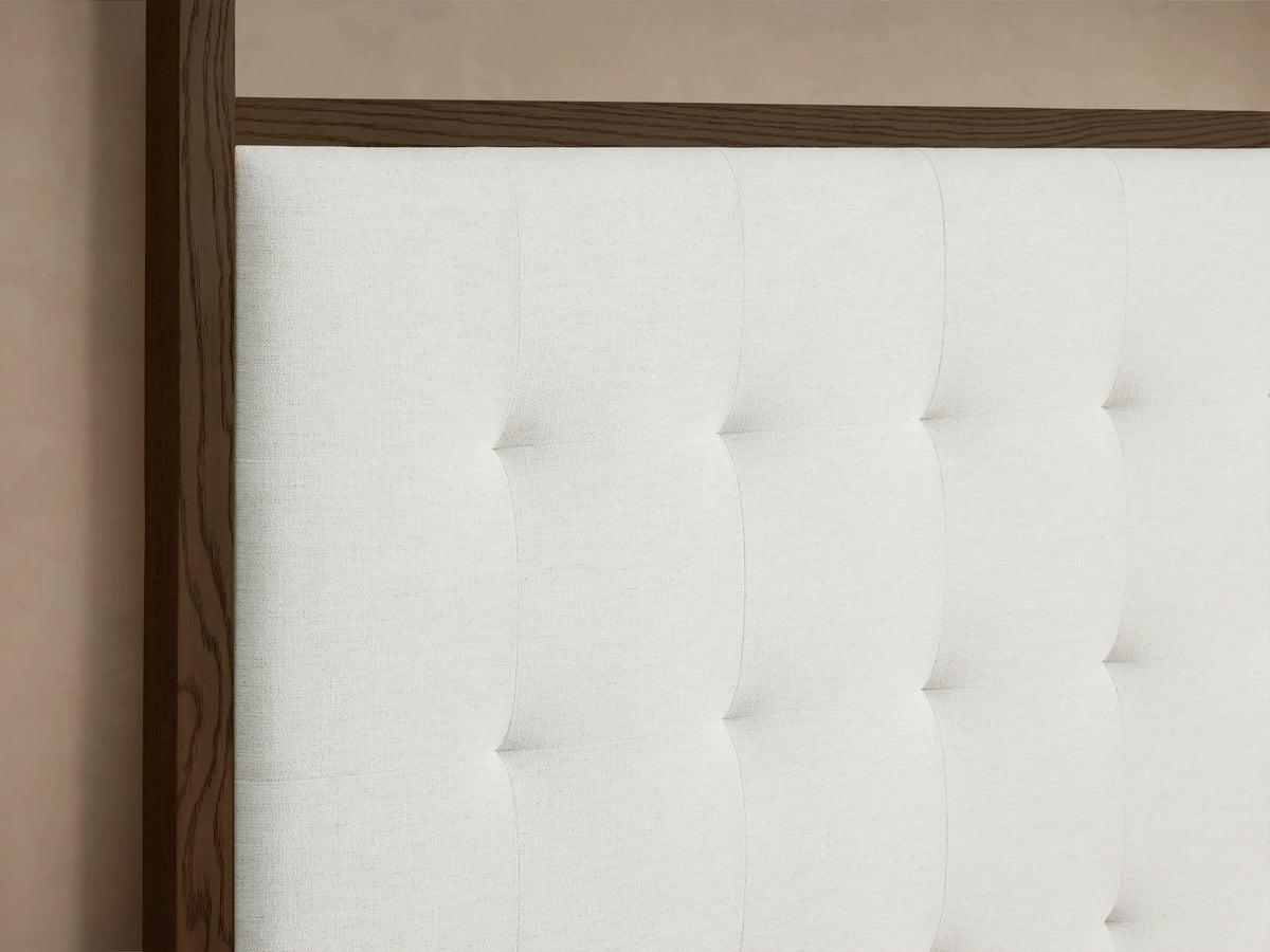 Front view of the Darien Box-Tufted Canopy Bed with a dark oak frame, white box-tufted headboard, and white upholstered base.