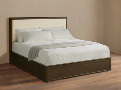 Conley Panel Bed with dark oak frame & cream upholstered headboard. Bed has white textured bedding & a gray throw blanket.