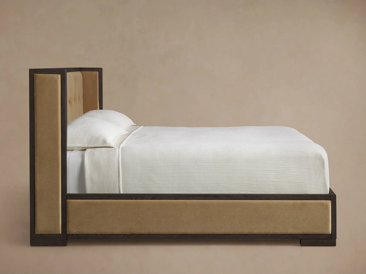 Darien Box-Tufted Shelter Bed. Angled close-up of dark oak frame and beige box-tufted upholstered headboard.