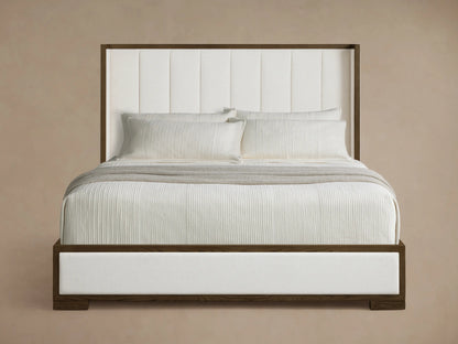 Angled front view of the Darien Channel-Stitched Shelter Bed with white channel-stitched upholstery, dark wood frame, dressed in white bedding.