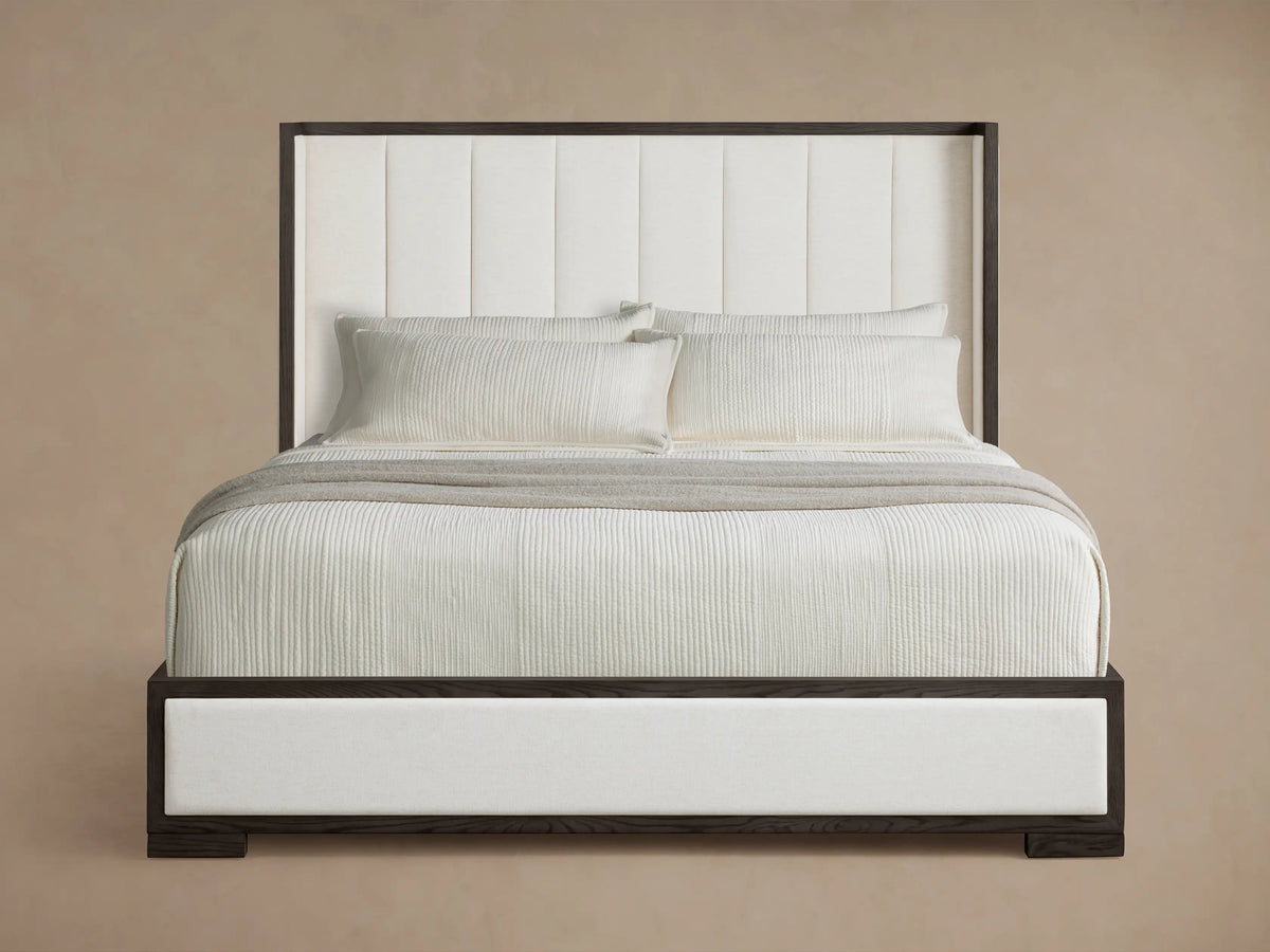 Darien Channel-Stitched Shelter Bed with dark oak frame and white channel-stitched upholstery, white bedding on wood floor.