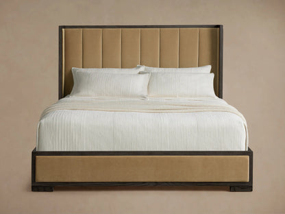 Darien Channel-Stitched Shelter Bed, dark oak frame with tan upholstered headboard & rails. White bedding on light wood floor.