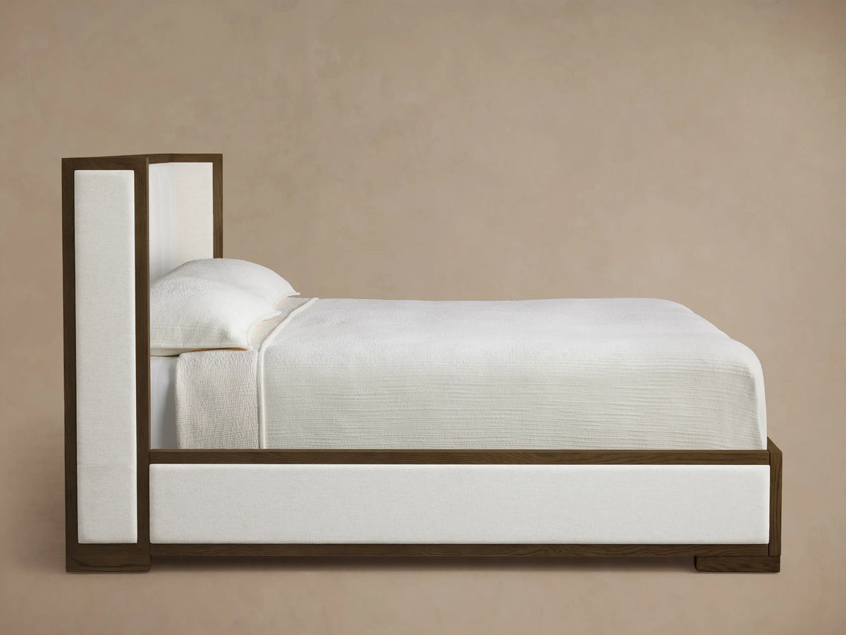 Close-up of the brown oak frame corner with cream woven fabric and channel-stitched panels of the Darien Channel-Stitched Shelter Bed.
