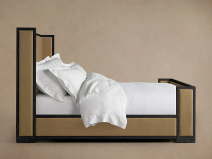 Darien Shelter Bed with high footboard, oak frame with upholstered panels, shown from side, with white bedding and pillows.