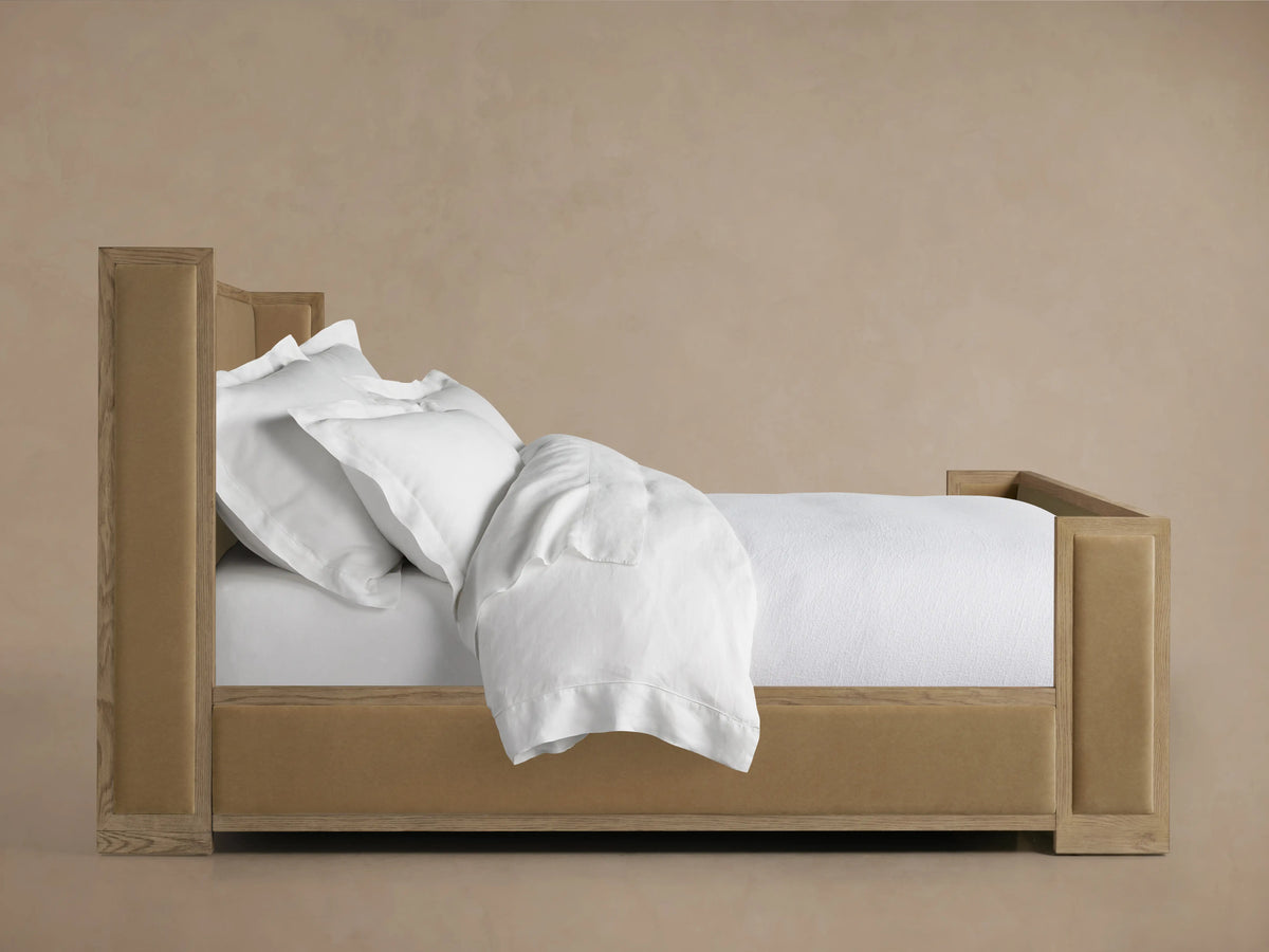 Darien Shelter Bed with High Footboard in oak wood, features upholstered beige headboard and footboard, white bedding neatly arranged.