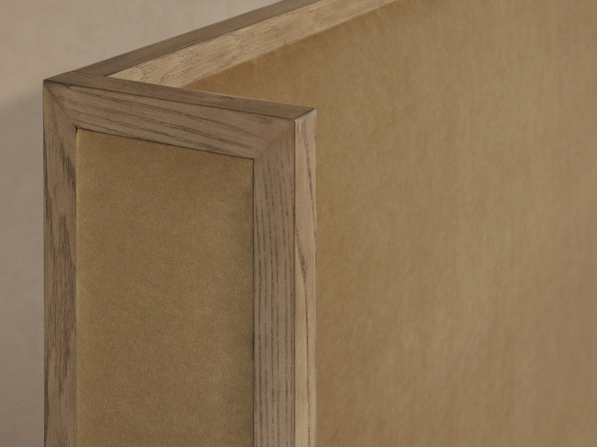 Corner view of the Darien Shelter Bed's high footboard showing oak veneer frame and upholstered beige panel in a close-up shot.