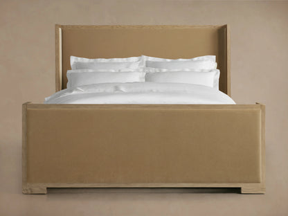 Darien Shelter Bed with high footboard, oak veneer and solid oak frame, upholstered panels, with white bedding in a warm-toned room.