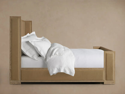 Darien Shelter Bed in oak with high footboard and upholstered headboard, positioned in a neutral-toned room with white bedding.