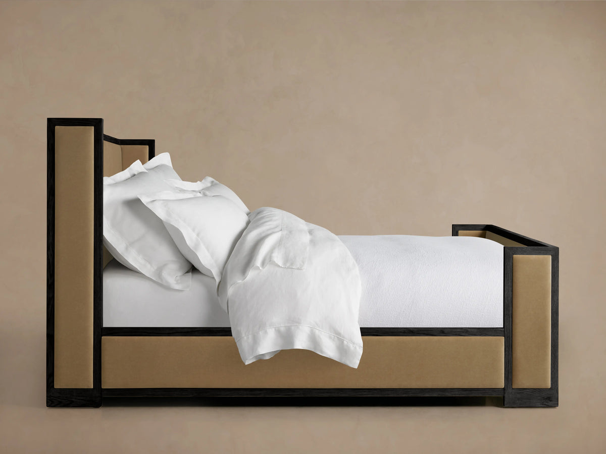 Darien Shelter Bed featuring high footboard, oak frame, and upholstered panels. Side view with white bedding on a neutral background.
