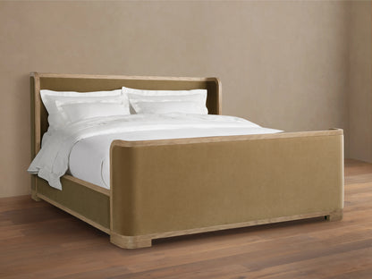 Darien Curved Shelter Bed in oak with high footboard, beige upholstered panels, white bedding, on wooden floor, side view.