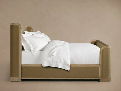 Curved corner of Darien Curved Shelter Bed's high footboard with oak veneer and upholstered tan paneling.