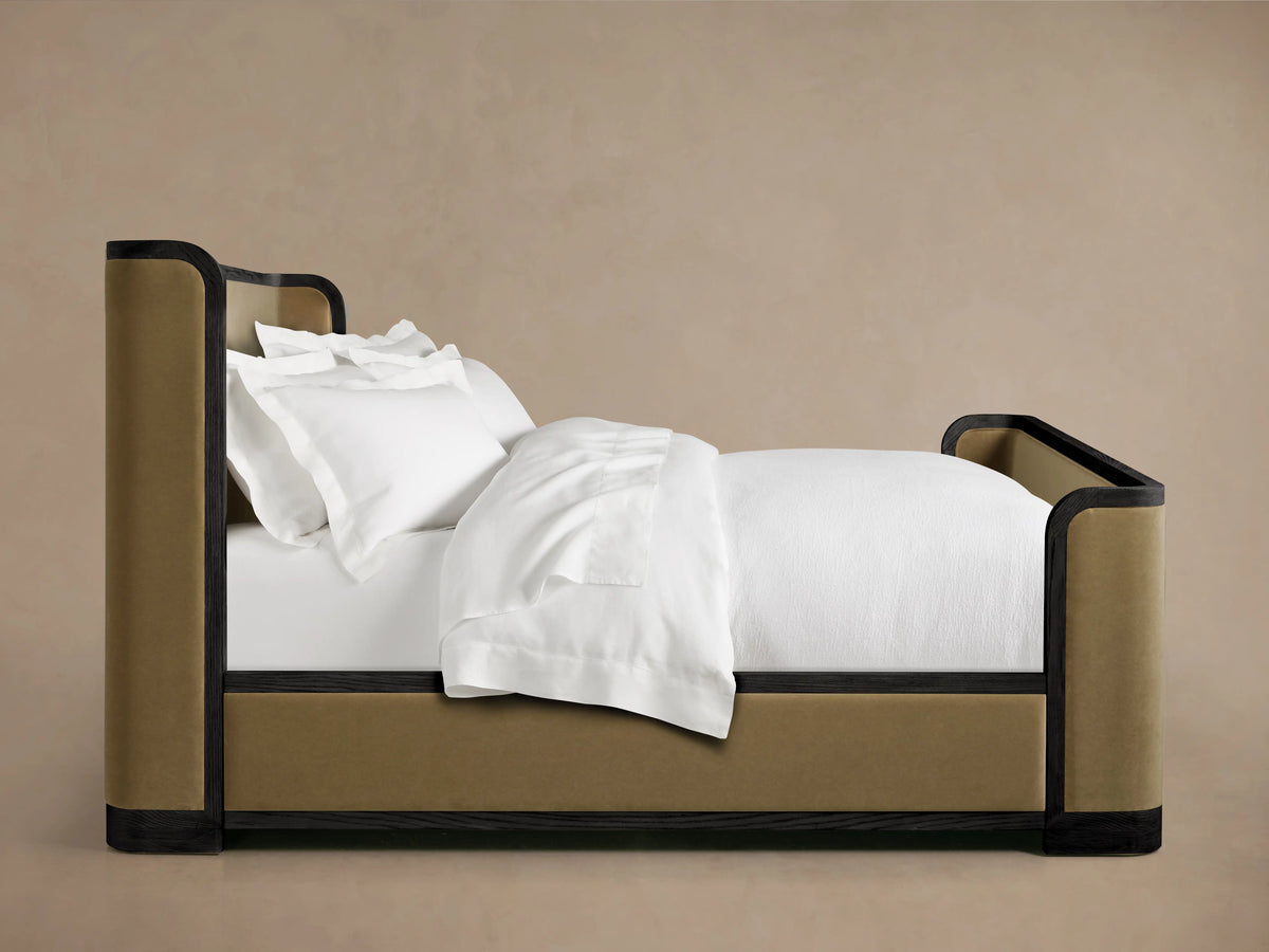 Darien Curved Shelter Bed featuring a high footboard with upholstered panels in oak finish, topped with white bedding.