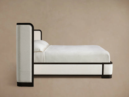 Darien Extended Curved Shelter Bed close-up. Dark oak frame with visible grain curves around light, textured upholstered panels.
