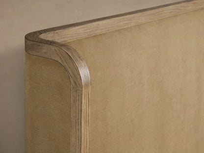 Darien Curved Shelter Bed with a low footboard, oak wood frame, upholstered panels, white bedding, against a beige wall.