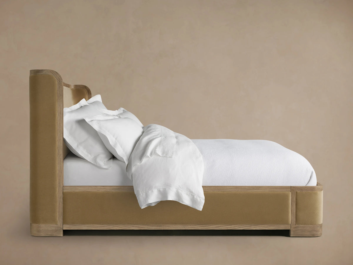 Darien Curved Shelter Bed with low footboard, oak frame and upholstered panels, dressed in white bedding in a neutral room.