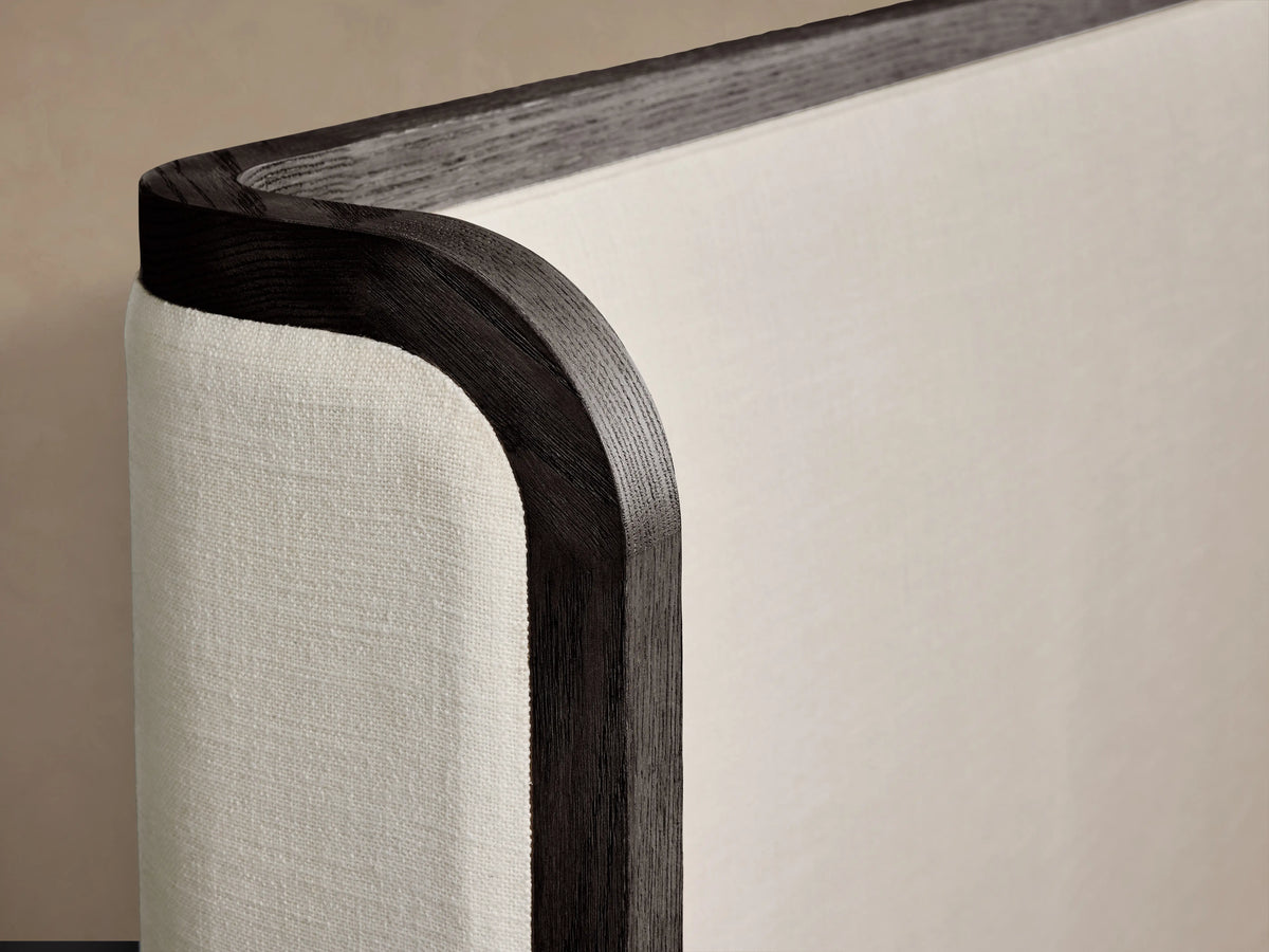 Darien Curved Shelter Bed with low footboard, oak veneer frame, upholstered panels, white bedding, against beige wall.