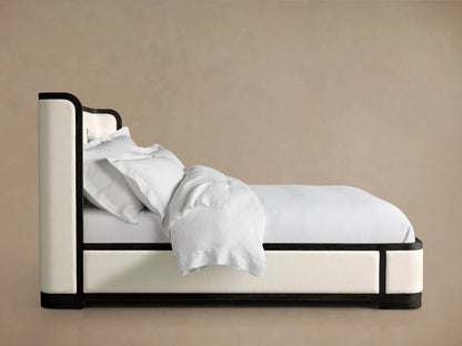 Darien Curved Shelter Bed with white upholstered panels, curved headboard, and low footboard against a beige background.