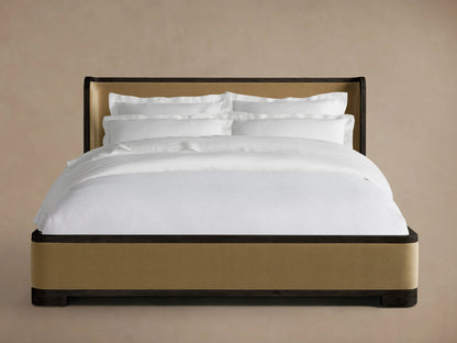 Darien Curved Shelter Bed with Low Footboard, oak frame, upholstered panels, white bedding, side view against beige background.