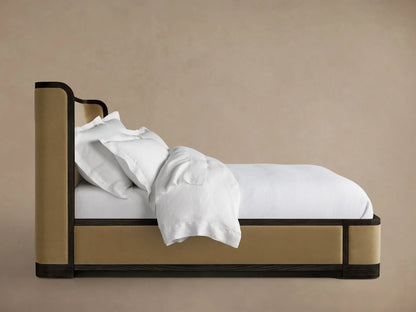 Darien Curved Shelter Bed in oak with upholstered panels, showing low footboard and white bedding, against a neutral background.