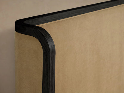 Curved corner detail of the Darien Curved Shelter Bed's headboard, showing oak wood with a dark finish and beige upholstered panel.