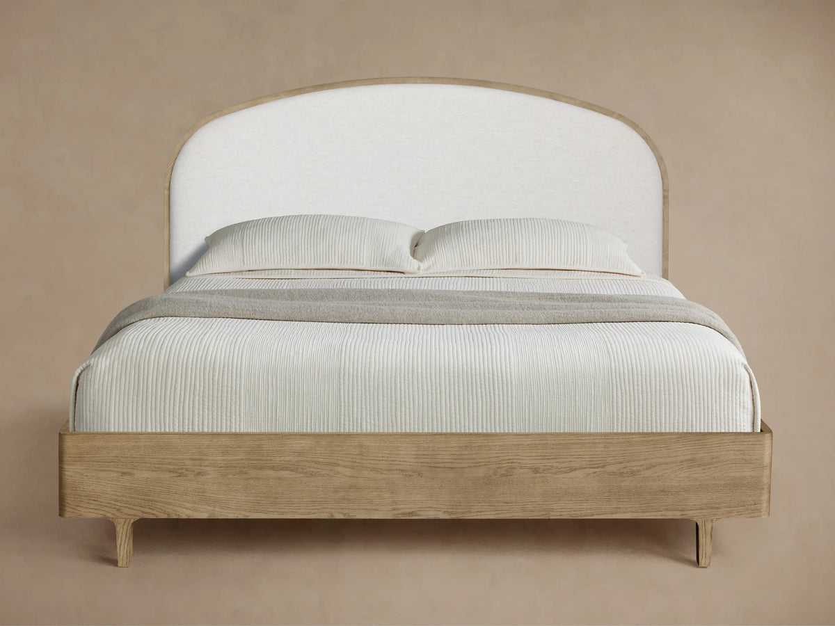 Danny Bed with light oak wood frame, curved white upholstered headboard, white ribbed bedding, and a grey throw.
