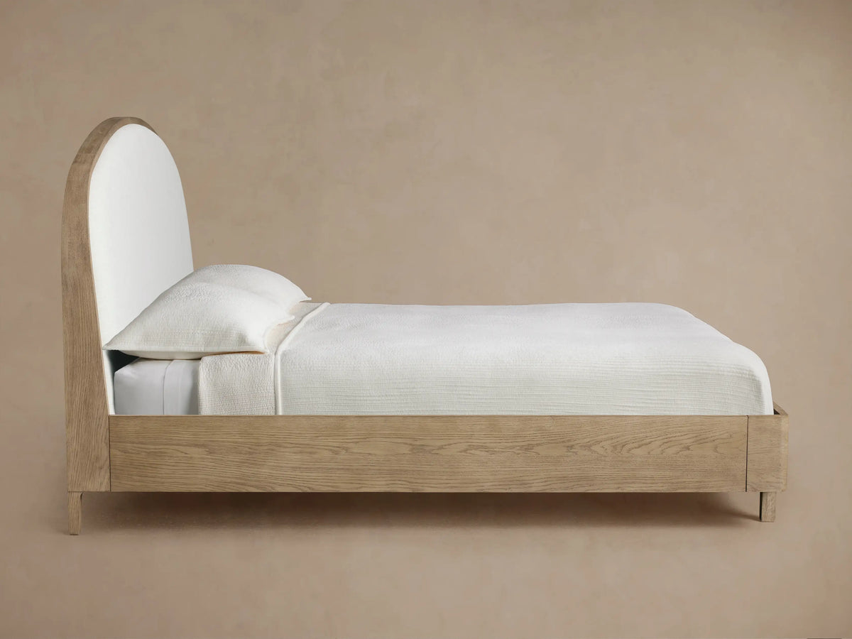 Close-up of Danny Bed headboard showing a curved light oak wood frame and a textured, off-white upholstered panel.
