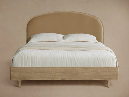 Danny Bed with arched tan upholstered headboard, light oak wood frame, white ridged bedding, and cream throw blanket.