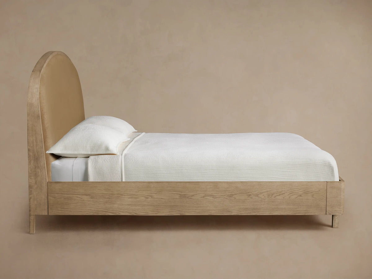 Danny Bed headboard close-up: curved oak frame with light wood finish, adjacent to a textured beige upholstered panel.