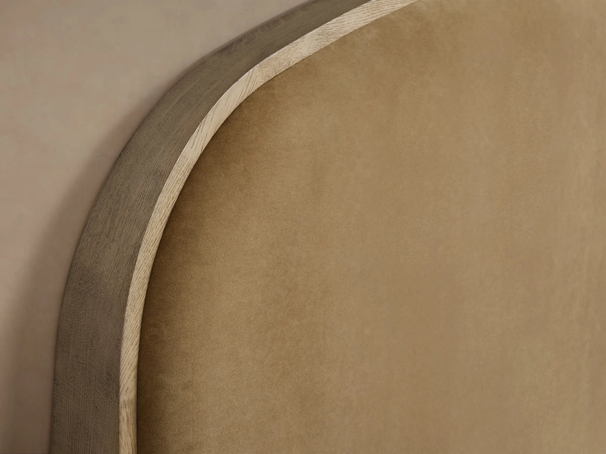 Danny Bed with arched tan upholstered headboard, light oak frame, white ribbed bedding, and neutral throw blanket.