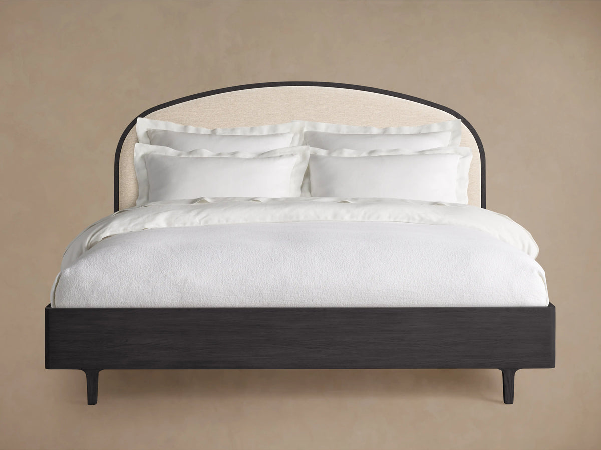 Danny Bed with arched cream upholstered headboard framed in dark wood, dark wood frame & short legs, crisp white bedding.