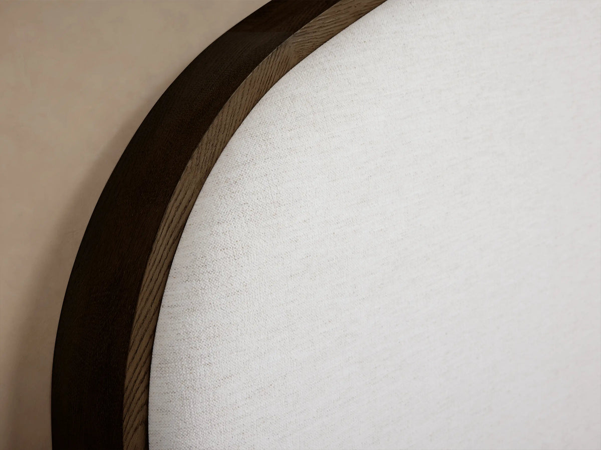 Close-up of the rounded dark oak wood frame and white upholstered fabric of the Danny Bed headboard.