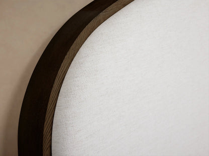 Close-up of the curved dark oak frame and cream upholstered headboard detail of the Danny Bed.