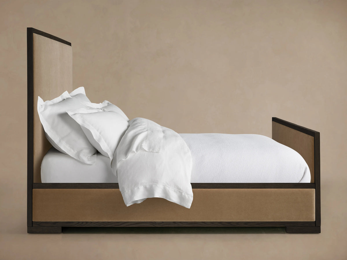 Darien Panel Bed with High Footboard in oak wood with an upholstered panel. White bedding is shown tucked in.