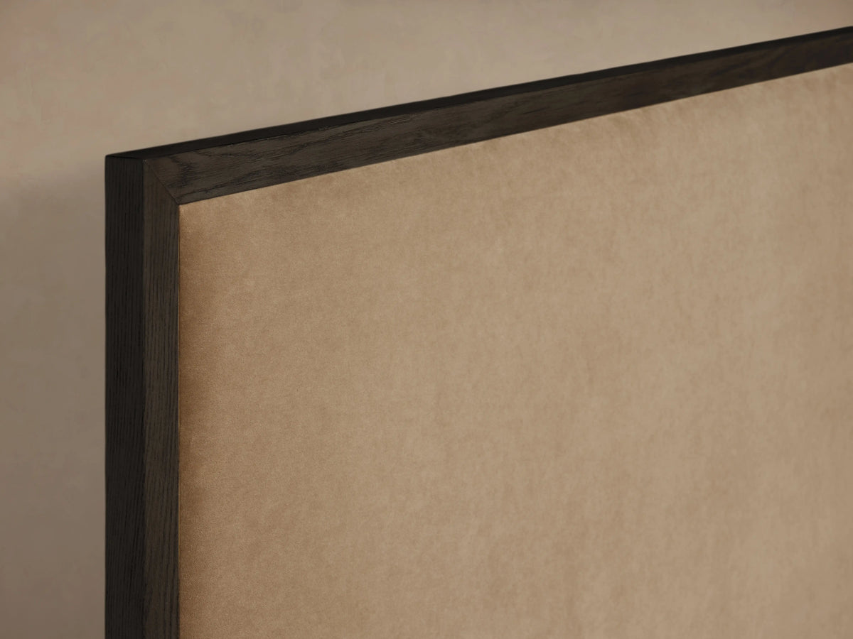 Darien Panel Bed's high footboard made of oak veneer with a dark wood frame, featuring beige upholstery.
