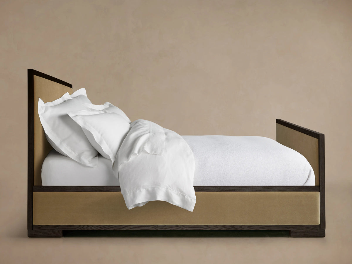 Darien Panel Bed with High Footboard, featuring dark oak frame, upholstered panels, and white bedding, set against a neutral background.