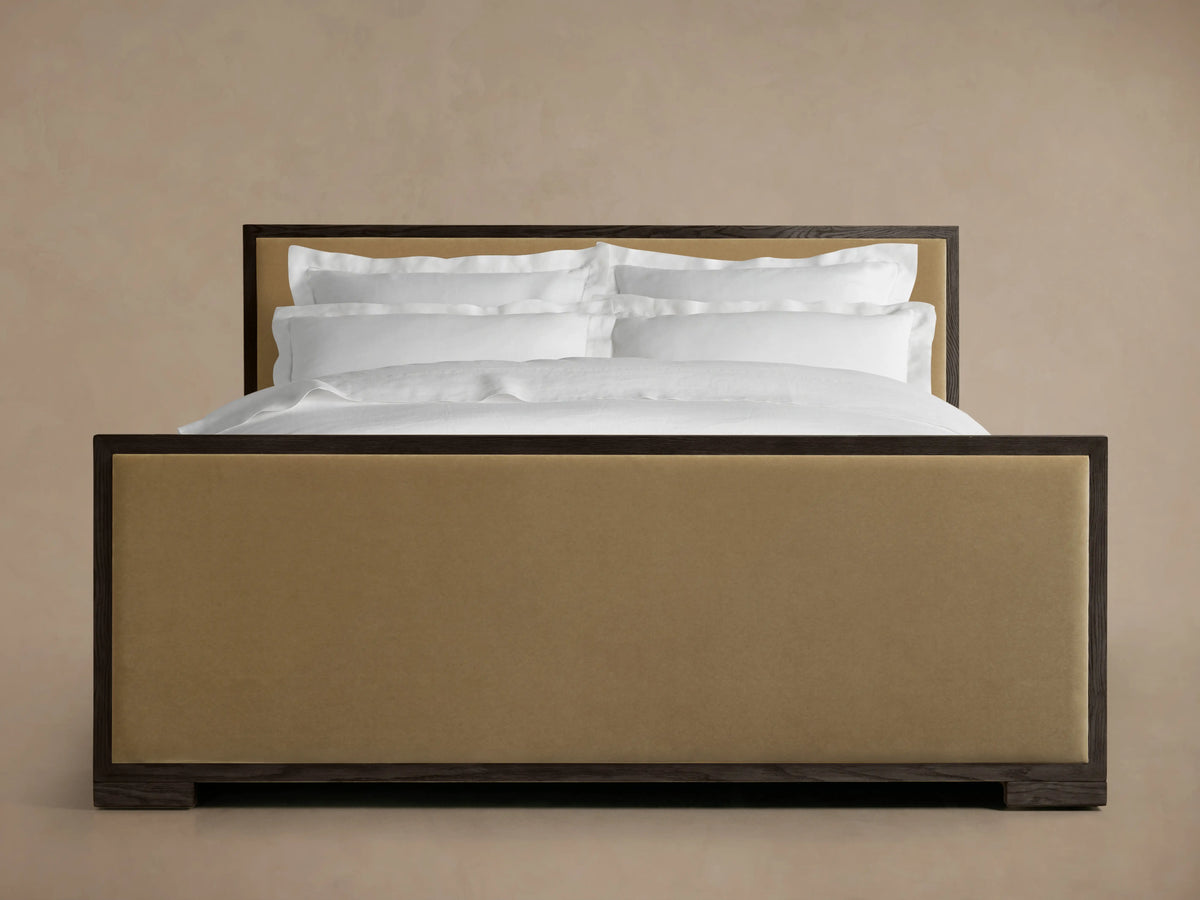 Darien Panel Bed with high footboard, oak veneer and solid wood, upholstered tan panels, white bedding, in a minimal room.