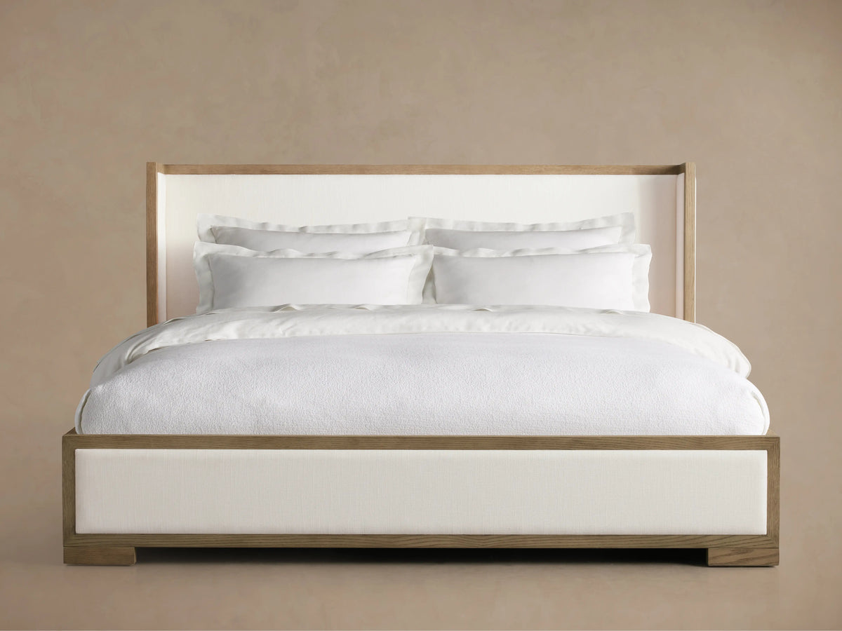 Darien Shelter Bed with Low Footboard in solid oak, featuring a tall upholstered headboard and white bedding, displayed against a neutral background.