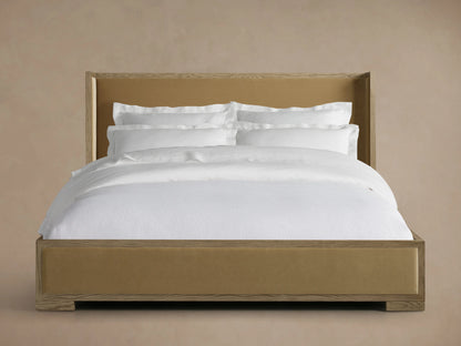 Darien Shelter Bed features a low footboard with oak veneer and upholstered panels, dressed in white bedding against a beige backdrop.