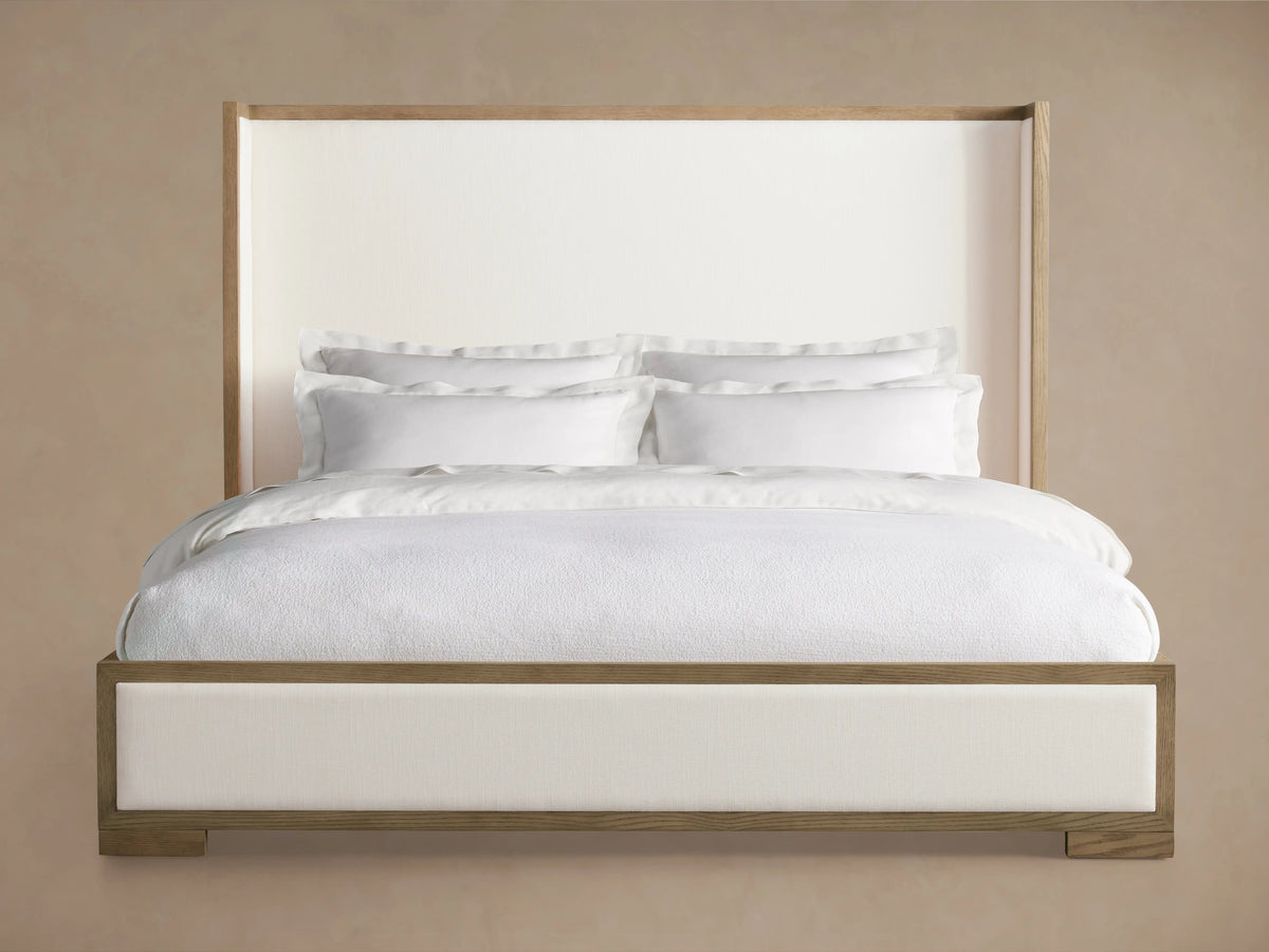 Darien Shelter Bed with low footboard, oak wood frame, white upholstered panels, white bedding, beige background.