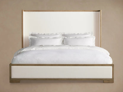 Darien Shelter Bed with low footboard, oak wood frame, white upholstered panels, white bedding, beige background.