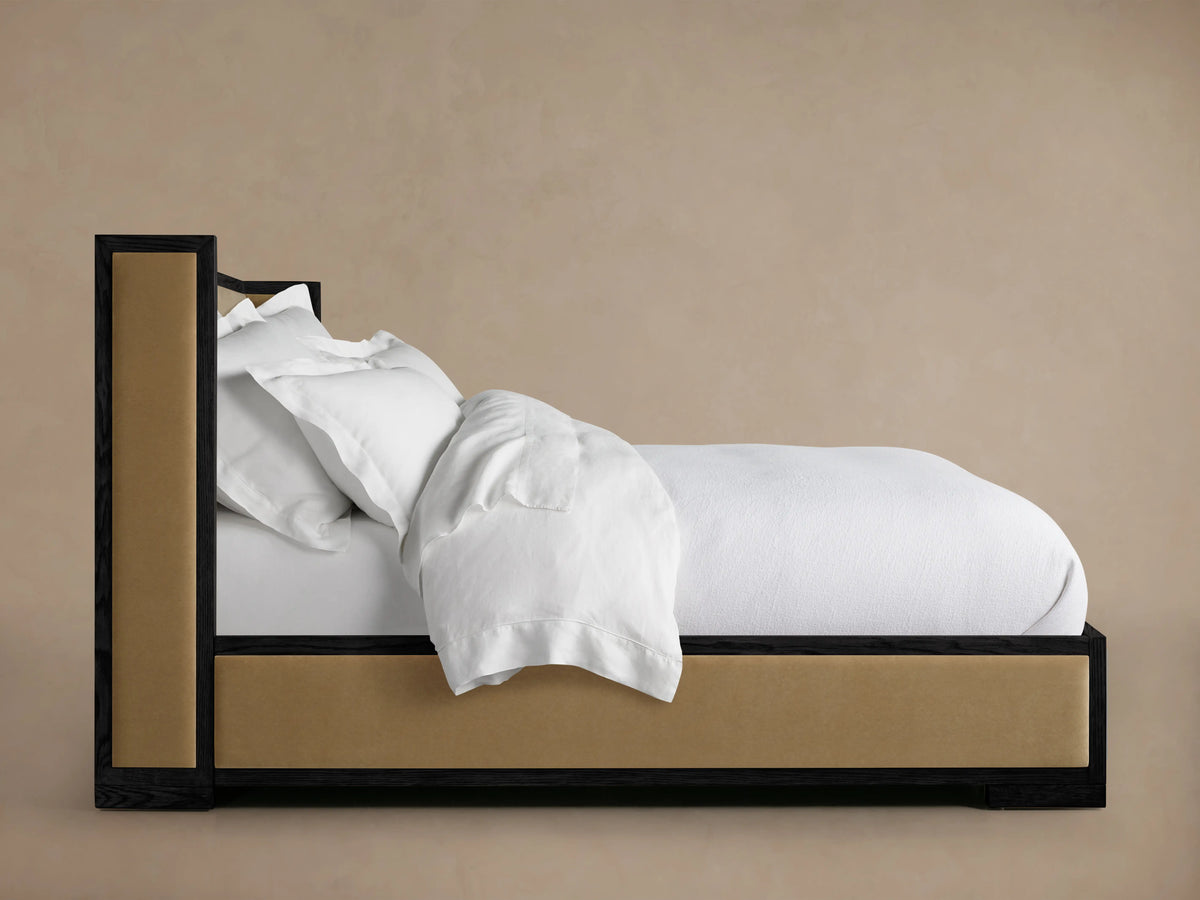 Darien Shelter Bed with Low Footboard, crafted from oak, featuring a dark wood frame and tan upholstered panels, fully made bed with white bedding.