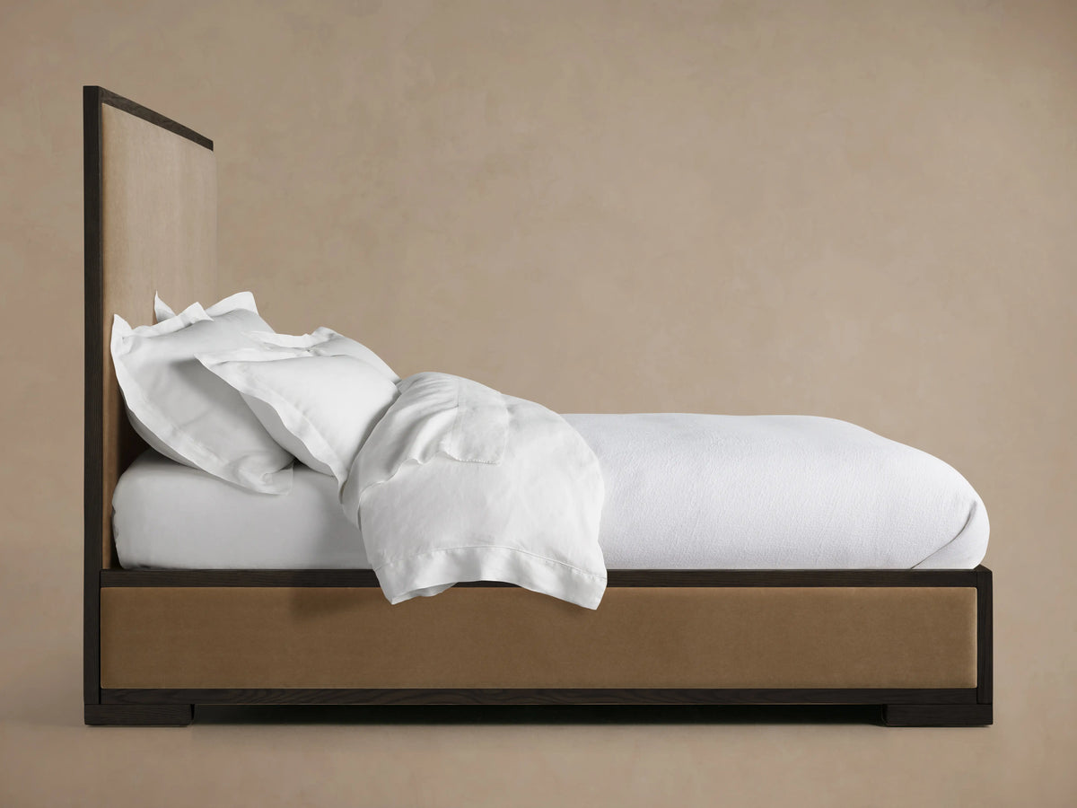 Darien Panel Bed with low footboard, oak veneer and solid wood frame, upholstered panels; white bedding tucked in, side view.