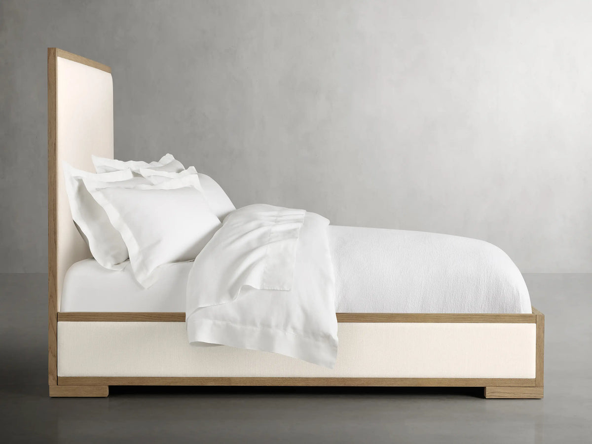 Close-up of the Darien Panel Bed headboard with oak wood frame and beige upholstered panel, showcasing craftsmanship.