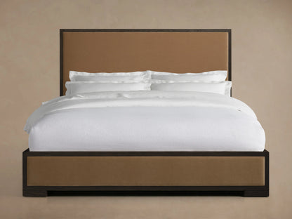 Darien Panel Bed with oak frame, low footboard, and upholstered panels, shown with white bedding in a neutral room.