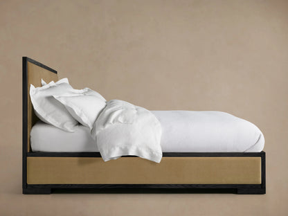 Darien Panel Bed with Low Footboard, featuring oak frame with upholstered panels, white bedding, against a beige wall.