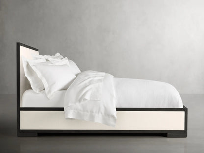 Alt text: Close-up of the Darien Panel Bed showcasing a dark oak frame with a cream upholstered panel.