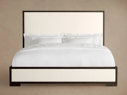 Darien Panel Bed with low footboard, featuring a dark oak frame with light upholstered panels, neatly made with white bedding.